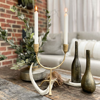 Decorative setup with a candelabra, antlers, and vases on a wooden surface.