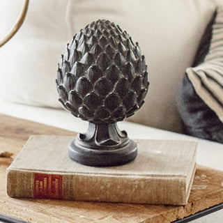 Decorative artichoke sculpture on a book with a blurred background