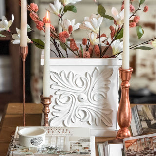 Decorative white vase with floral arrangement and candles on a table. European Cottage Steal It Box