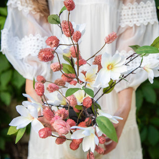 Person holding a bouquet of pink and white flowers with green leaves. European Cottage Steal It Box