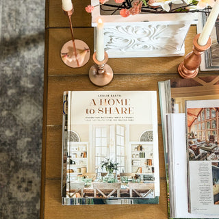 Book titled 'A Home to Share' on a wooden table with candles and decorative items. European Cottage Steal It Box