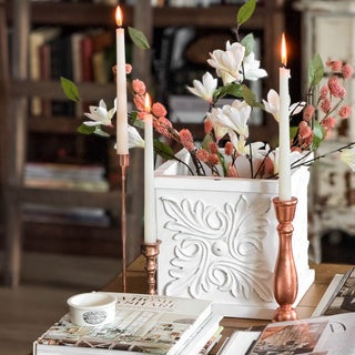 Decorative candle holders with an ornate white planter box with flowers on a table. European Cottage Steal It Box