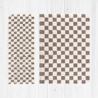 Two checkered rugs on a white wooden floor.