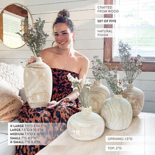 Woman showcasing a set of five handcrafted wooden vases
