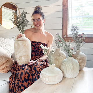 Woman sitting on sofa holding handcrafted wooden vase