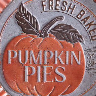 Detailed close-up of embossed pumpkin pie design with 'Fresh Baked' lettering on metal wall sign