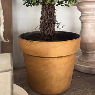 Close-up of distressed gold pot and faux boxwood tree trunk in home décor display