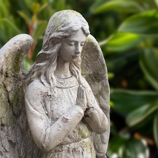 Side view of angel statue with detailed wings and praying pose, resin garden ornament with aged finish.