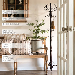 Tall wooden and iron coat rack with labeled product details styled beside a rustic bench and greenery in a farmhouse foyer