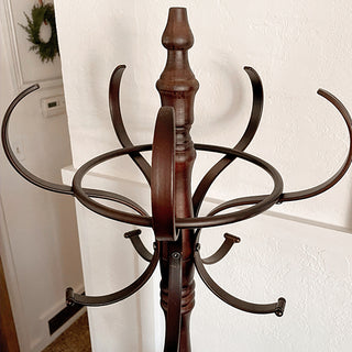 Close-up of top iron hooks on vintage wood and iron coat rack showing curved metal detailing.