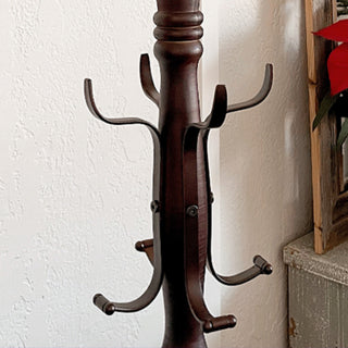Detailed view of lower metal hooks on wooden coat rack with antique-style home decor in background