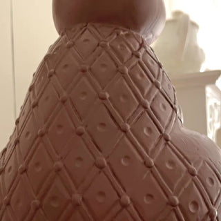 Close-up of a textured brown ceramic vase with geometric pattern