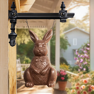 Decorative chocolate bunny hanging on a garden gate with a blurred garden background