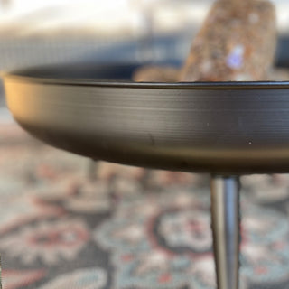 Macro detail of the rim and leg of a black metal fire pit bowl, highlighting texture and craftsmanship.