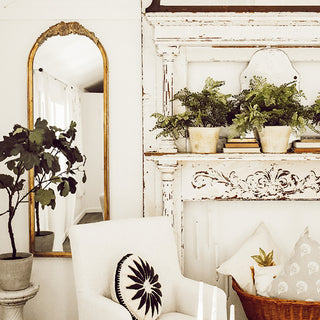 Gold arched mirror beside distressed white hutch