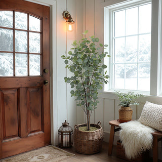 Nestled corner of an entryway with a wooden door, life like potted plant, and bench with a pillow.