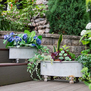 Set of galvanized metal planters with faux greenery and red berry accents displayed on a stone outdoor fireplace, rustic home décor planters for patio or garden