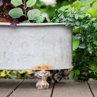 Footed galvanized planter with cascading greenery on wooden deck