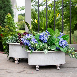 Pair of galvanized metal planters filled with mixed greens on outdoor porch