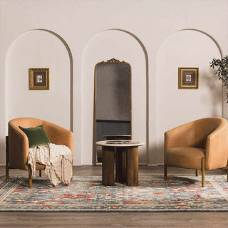 Two brown armchairs with a small table and decorative elements in a room with arches and framed pictures.
