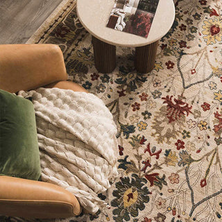 Floral patterned rug with a brown armchair and small round table.