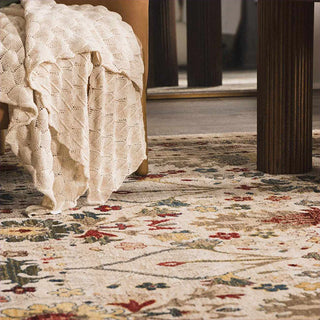 Floral patterned rug with a textured blanket draped over furniture