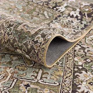 Close-up of a sage green patterned rug with a roll of rug pad underneath.