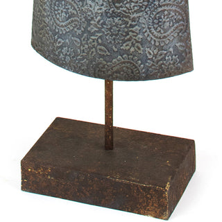 Close-up of the metal angel figurine’s embossed patterned skirt and rustic square metal base.