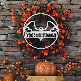 Close-up of metal bat wall sign with “Gone Batty” design on fall wreath with orange accents