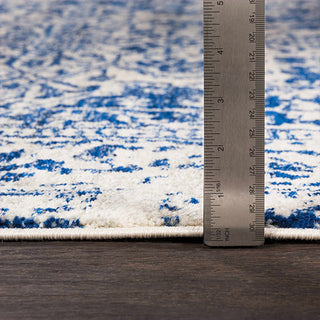 Rug with blue and white pattern next to a ruler for size reference