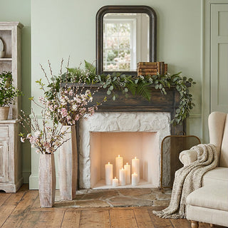 Cozy rustic fireplace with candles and greenery