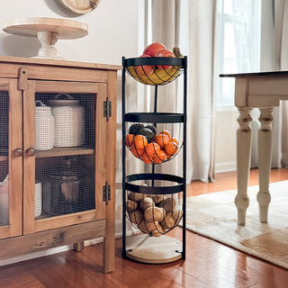 Three-tier black metal and wood floor-standing fruit basket rack filled with apples, bananas, oranges, and potatoes beside a rustic wood kitchen cabinet.