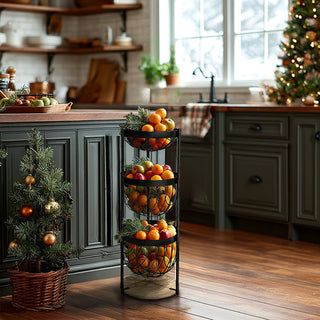 Three-tier fruit basket stand holding assorted citrus and apples in a cozy holiday kitchen with dark green cabinets and Christmas décor.