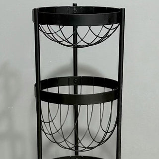 Empty three-tier black wire fruit basket stand against a neutral wall.