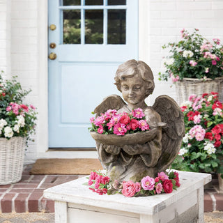 Distressed angel statue with bird feeder bowl on white porch with blue door and pink flowers