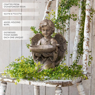 Vintage angel holding bowl garden statue with detailed wings against white background