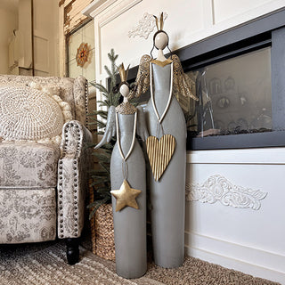 Distressed gray metal angel figurines with gold filigree wings displayed beside fireplace mantel Christmas holiday decor