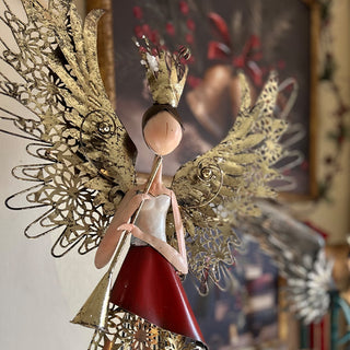 Close-up of red and gold metal angel figurine showing intricate wing detail and distressed finish craftsmanship