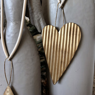 Corrugated gold heart ornament accent on tall angel figurine with vertical striped texture