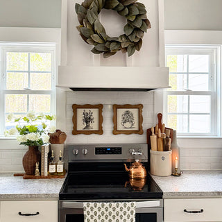 Kitchen with stove, decorative wreath, and framed pictures.
