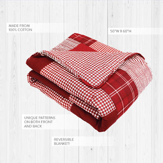 Folded reversible cotton Christmas quilt showing gingham check and windowpane plaid pattern detail on white wood background