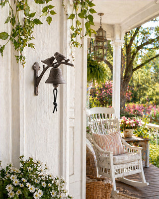 Cast iron bird door bell mounted on white porch column