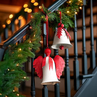 Vintage inspired Christmas bell decorations with antique white finish and red accents displayed on holiday decorated stairway railing