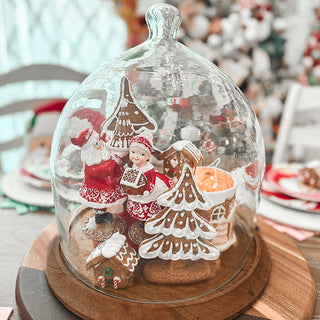 Holiday gingerbread scene inside decorative glass cloche