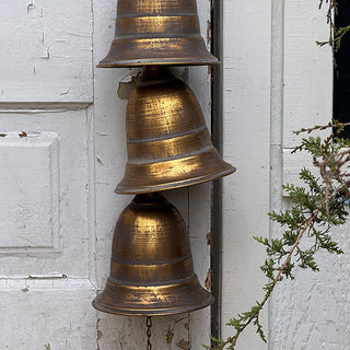 Detailed view of stacked distressed brass bells showcasing rustic texture and warm metallic finish.