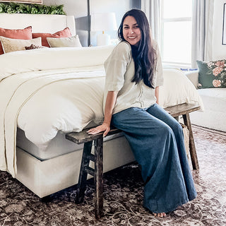 Woman sitting on rustic wood iron bedroom bench