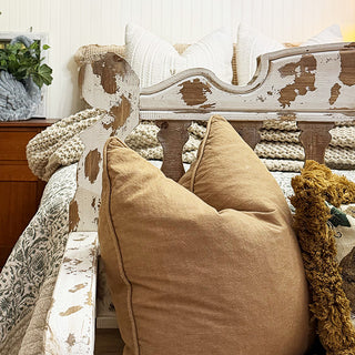 Decorative bench with distressed finish and pillows by a bed