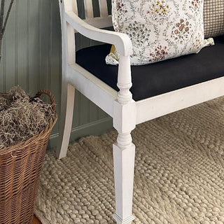Close-up white wooden bench leg and black cushion
