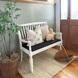 White farmhouse bench with pillows and woven basket