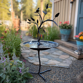 Elegant iron bird bath fountain in landscaped garden